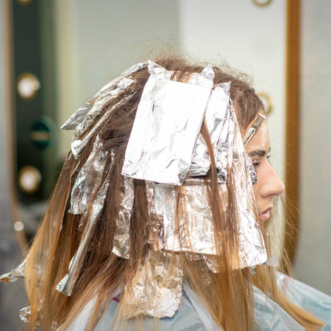 Woman getting her hair colored at a salon with foils.